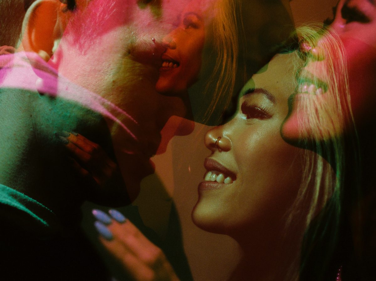 A medium format film double exposure on Cinestill 800T taken at night with ambient alleyway light and coloured video lights. The camera was a Pentax 645nii using 120 film. The couple is doubled while they look at each other during an anniversary portrait session.
