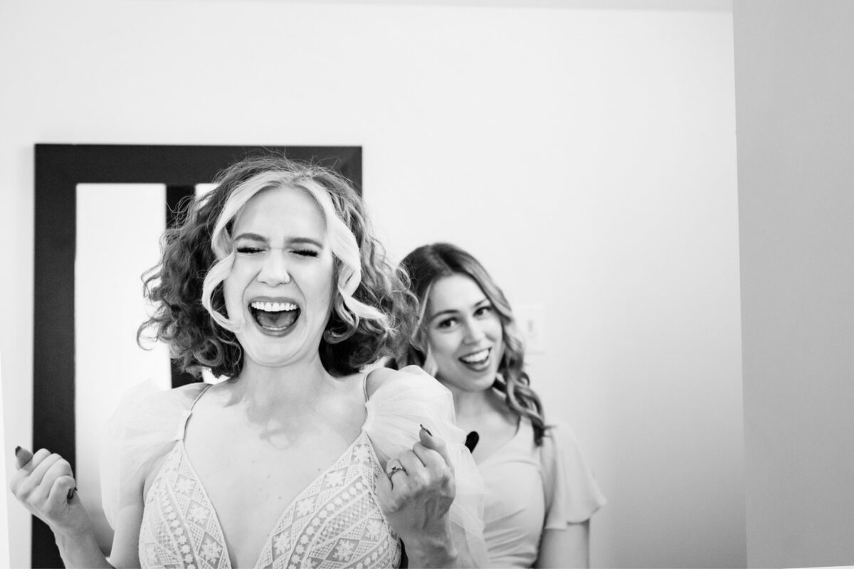 A happy joyful photojournalism documentary moment in black and white as a bride gets ready at the Parkside Hotel in downtown Victoria BC where they had their wedding