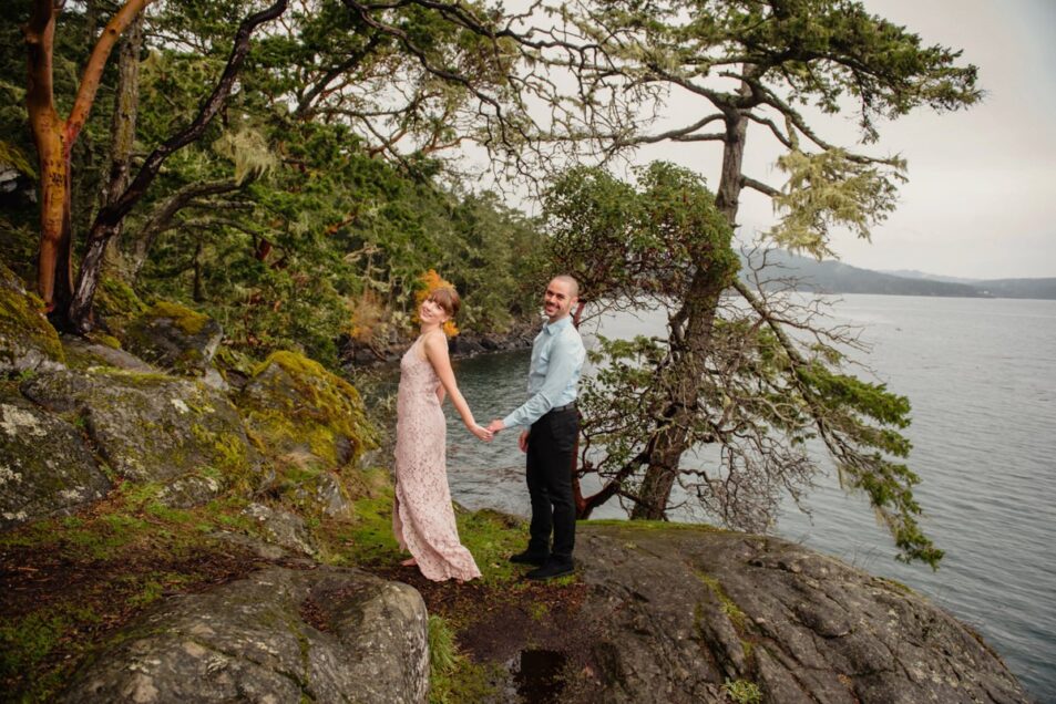 A bride in a pink dress at the rocky ocean hiking trail at East Sooke Park in Victoria BC