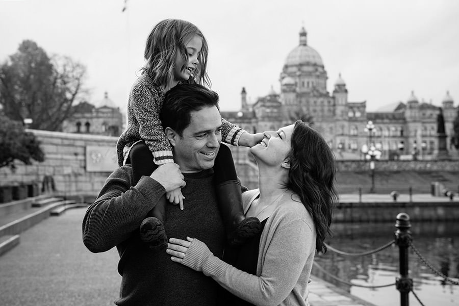 A family portrait session at Victoria B.C.'s inner harbour with the B.C. Legislature buildings in the background. This family portrait features a family of three with a five-year-old child.