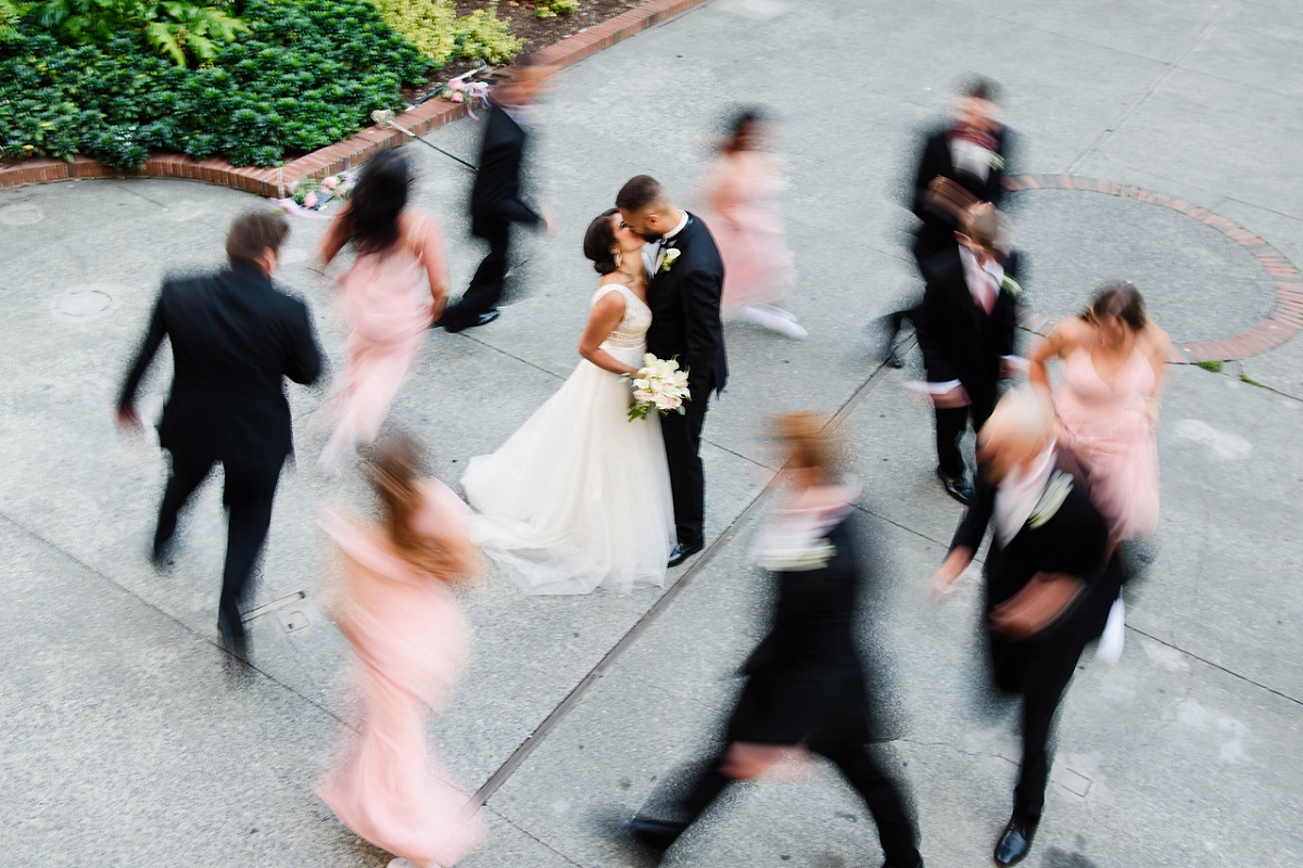 creative wedding photograph of a bridal party with motion blur circling around a newlywed couple in an urban setting at Bastion Square in Victoria BC
