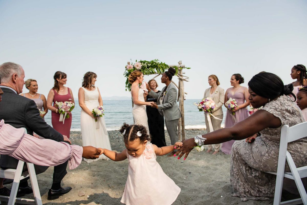 A cute funny picture of a girl playing in the aisle during her aunties wedding at Cordova Bay Beach House in Victoria BC