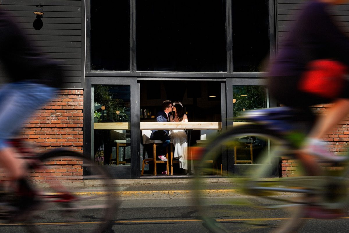 Best creative and artistic wedding portrait in downtown Victoria BC of a couple kissing and two bikes riding by with motion blur