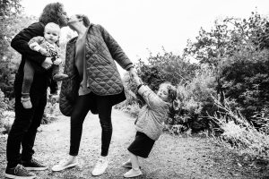A cute photo of a toddler pulling on her parents as they kiss during a fall mini session at Government House in Victoria BC