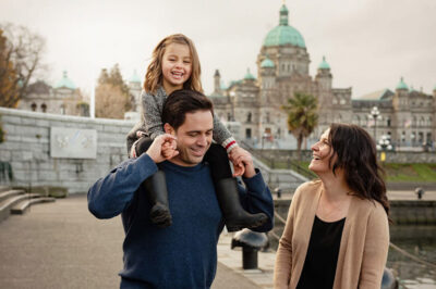 A view of the BC legislature for a lifestyle family photo of parents and their child on a fall day down at the Victoria inner harbour. It was taken by family photographer FunkyTown Photography.