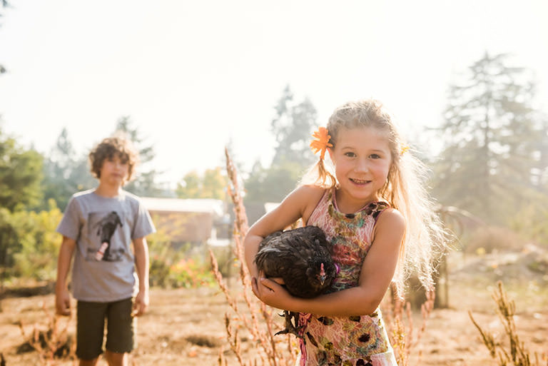 Photograph of a brother and sister with a chicken on their hobby farm taken by documentary family photographer Christina Craft in Victoria BC