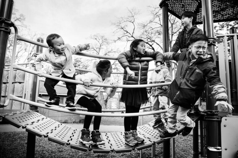 A group of young cousins playing and being themselves on a play apparatus at Beacon Hill Park in Victoria BC. This is a documentary family photo in black and white.