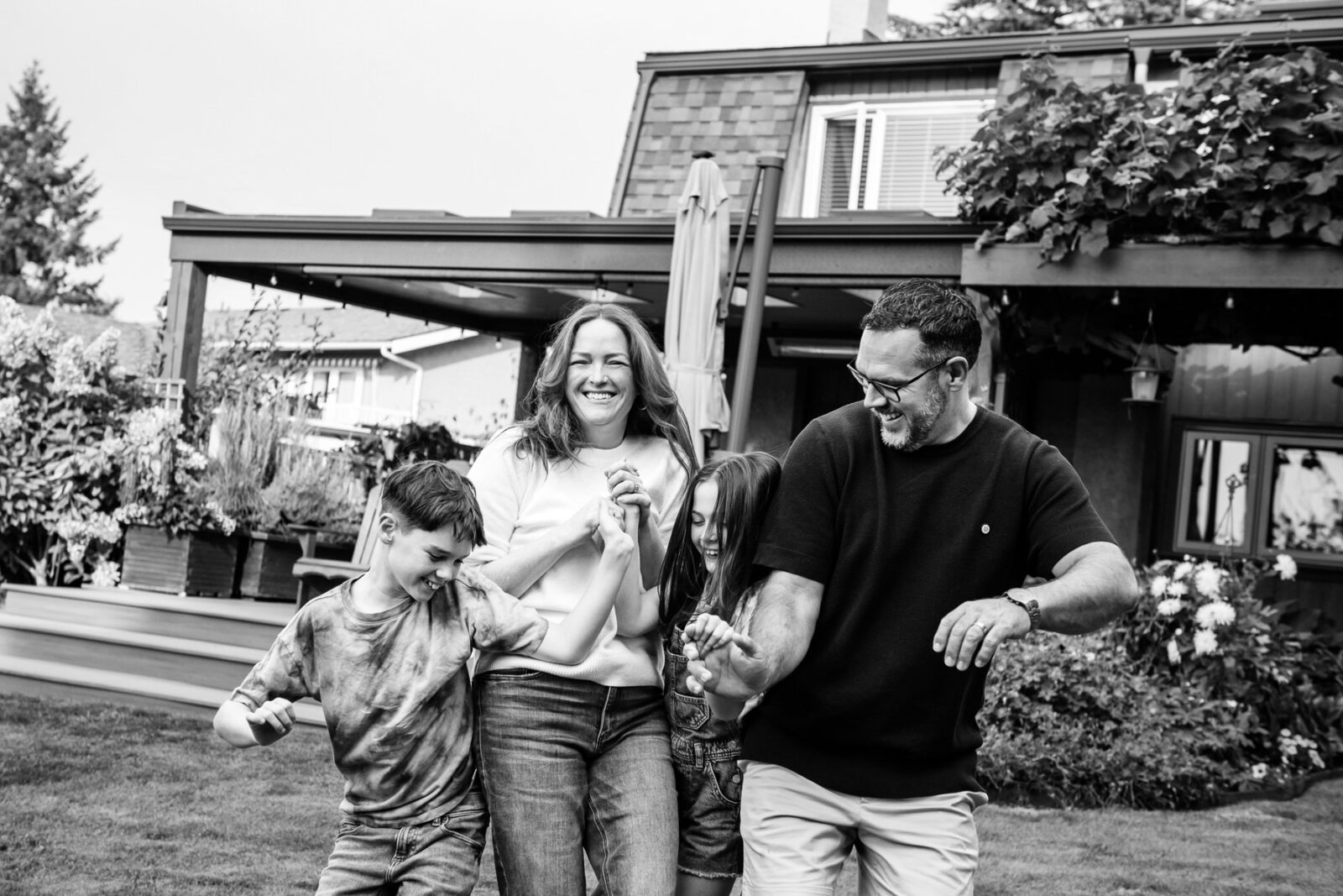 A family laughing as they play together in their backyard. The photo is a portrait in black and white.