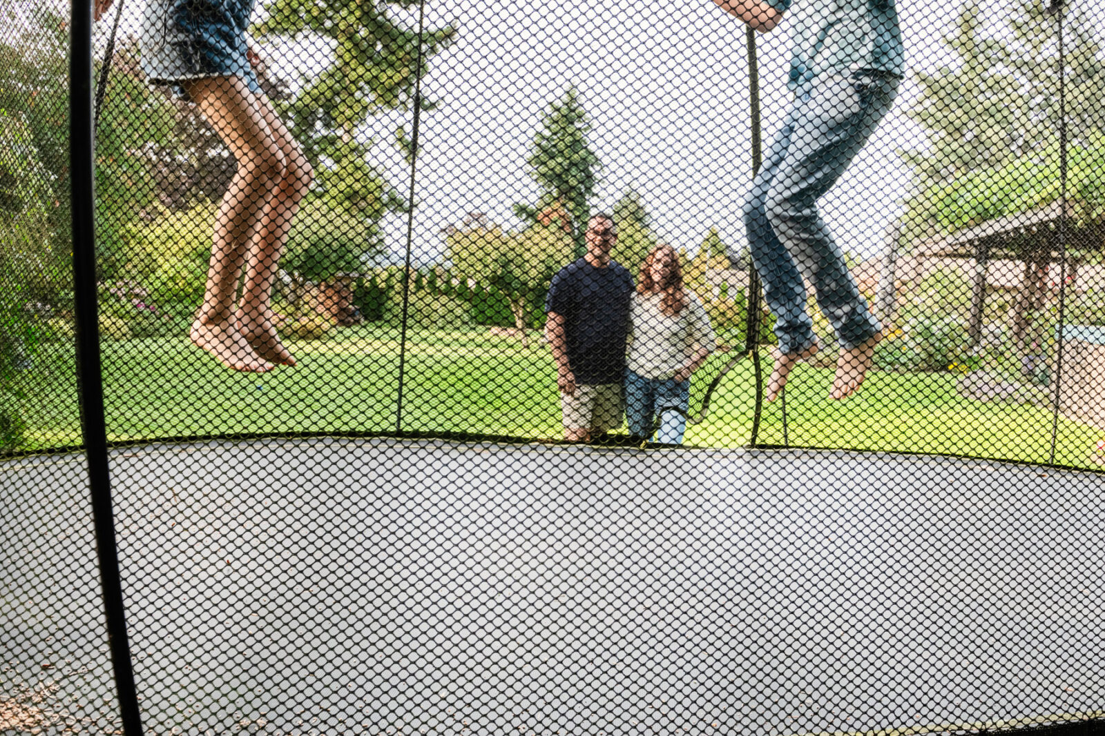 Two kids legs up in the air as they jump on a trampoline
