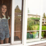 A brother and sister look out the window of their treehouse in their backyard in Victoria BC