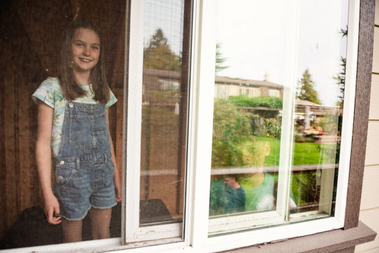 A brother and sister look out the window of their treehouse in their backyard in Victoria BC