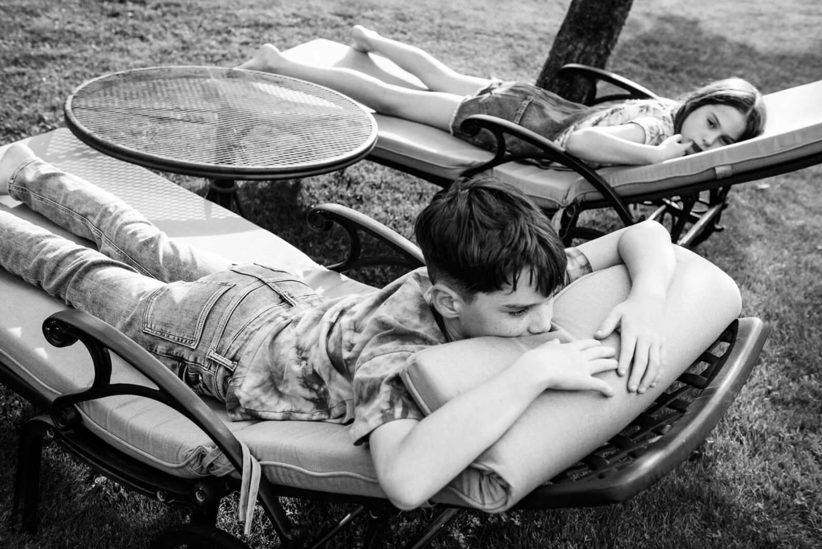 A photojournalism candid moment of two kids laying on lawn chairs and chilling out.