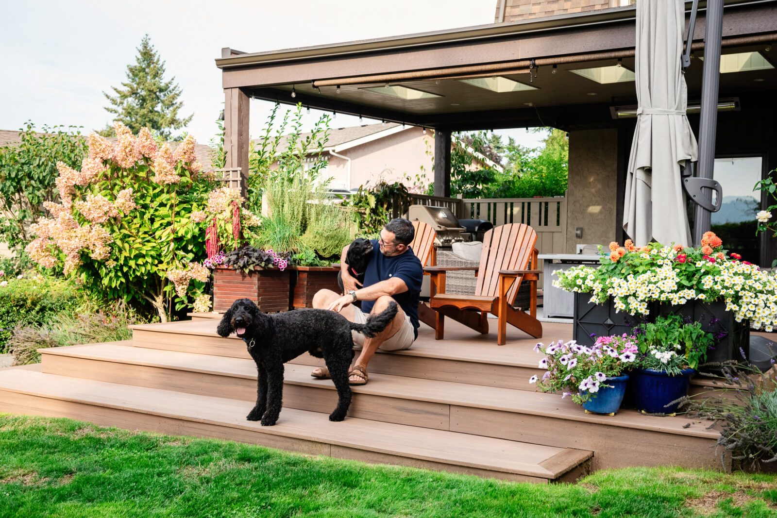 A dad sits on his back porch while his dog hangs out in the foreground.