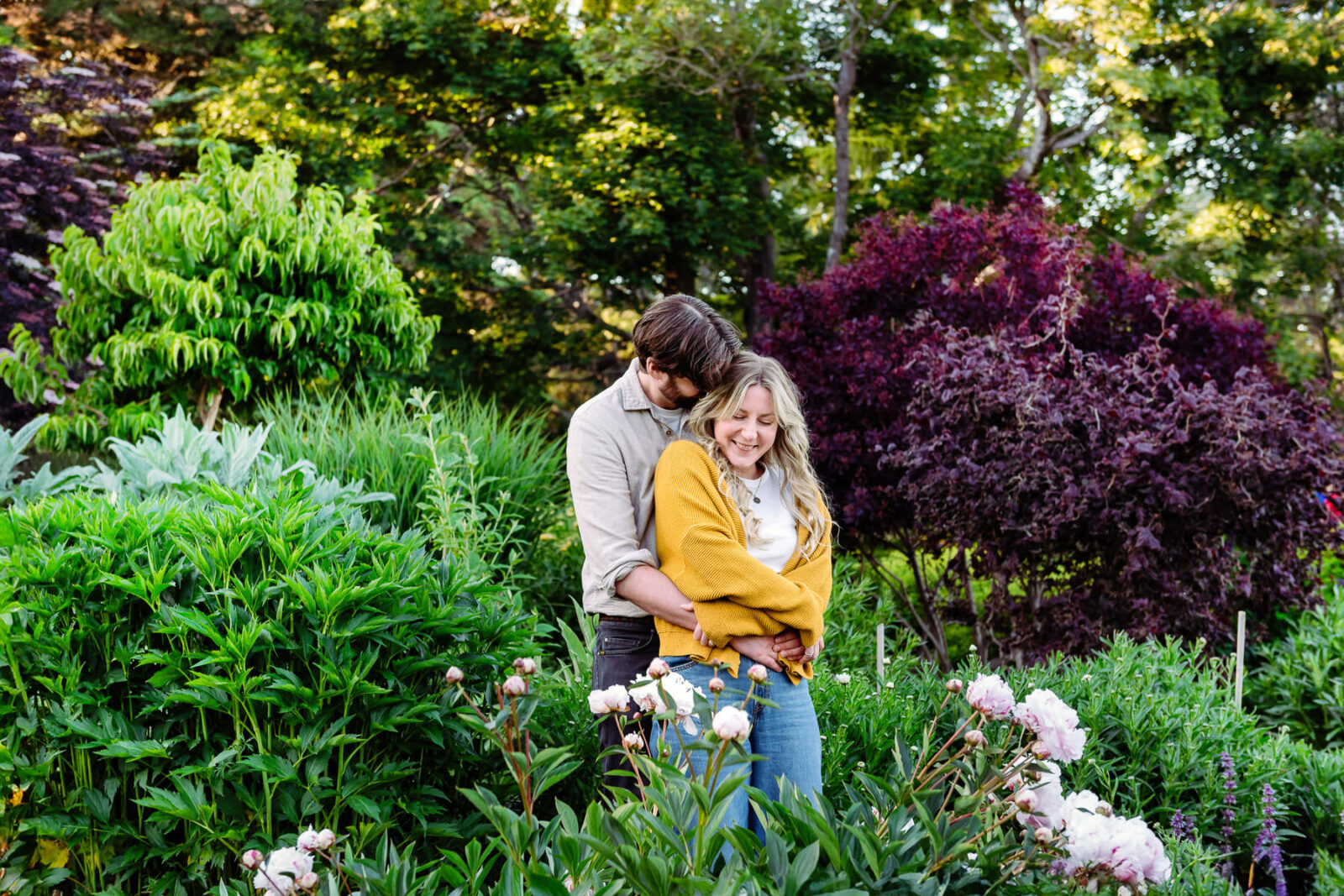 A couple snuggle surrounded by the garden in Beacon Hill Park