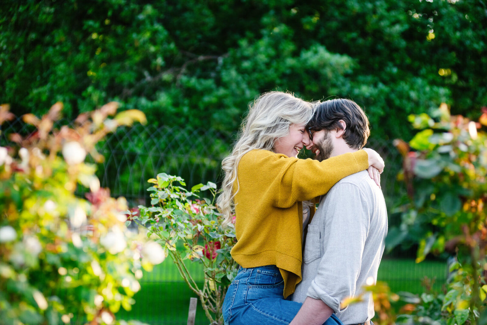 A beacon hill park engagement portrait photo of a couple who are snuggling among the flowers.