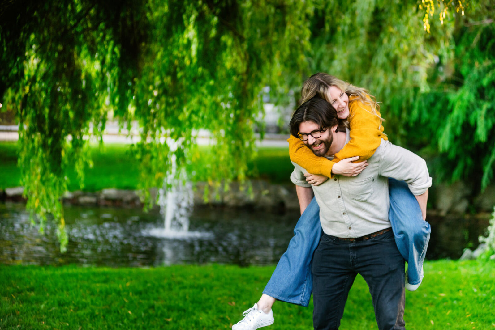 A guy gives his fiance a piggy back ride near one of the ponds at Beacon Hill Park in Victoria BC