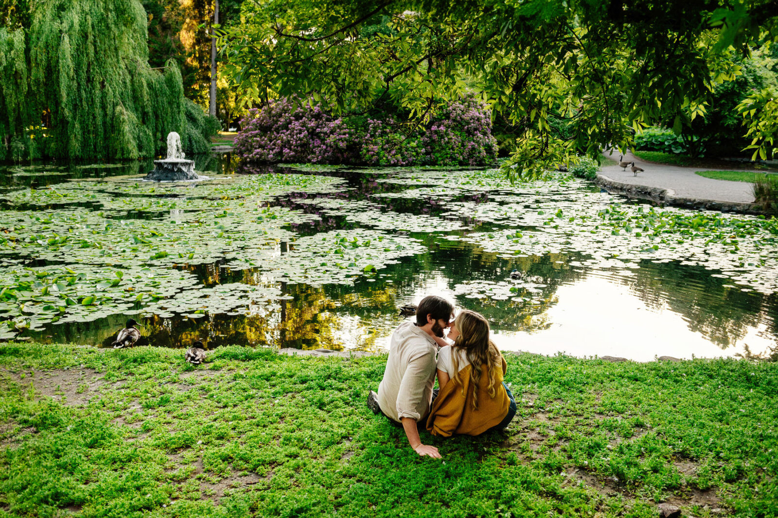 A couple sits at a lily pond in Beacon Hill Park in Victoria BC at sunset.