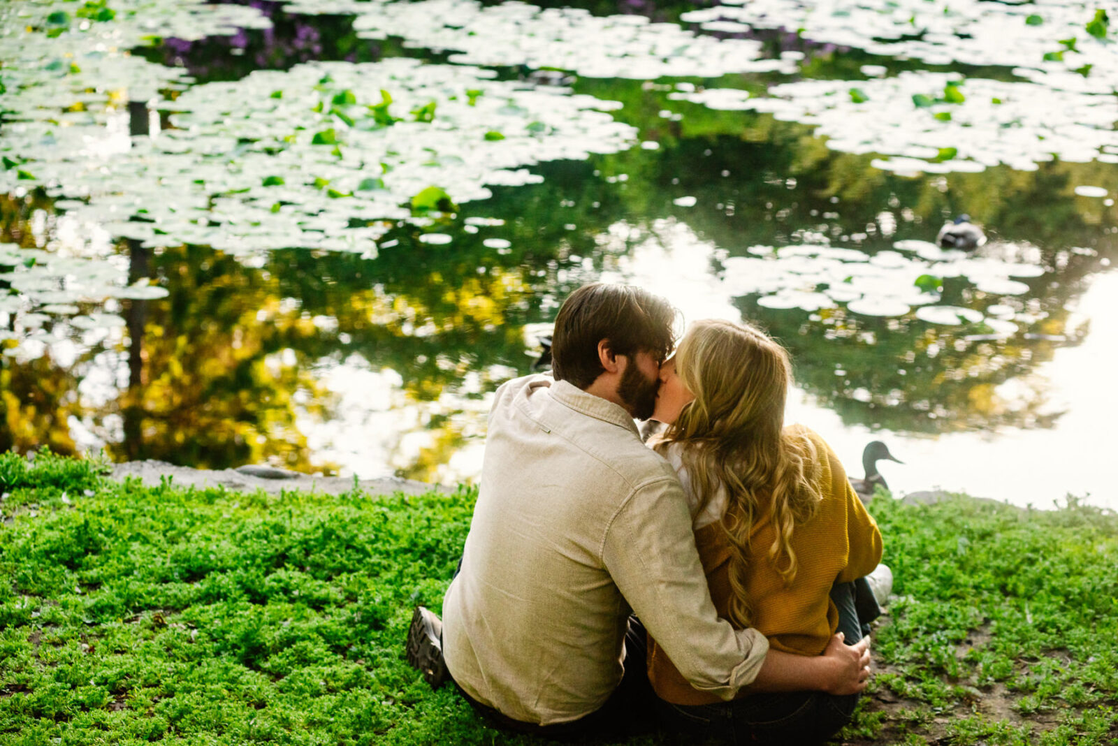 A couple sits at a lily pond in Beacon Hill Park in Victoria BC at sunset.