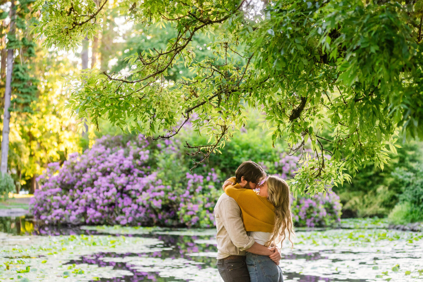 A couple kisses in front of the lily pond at Beacon Hill Park in Victoria BC