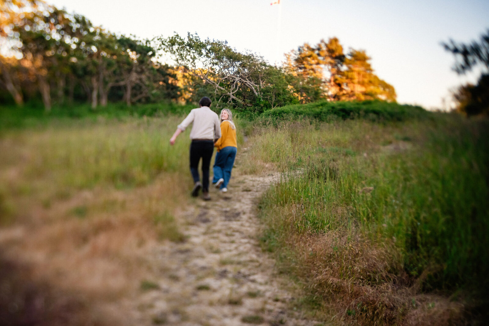 A tilt shift portrait of a couple running in the field behind Beacon Hill Park in Victoria BC