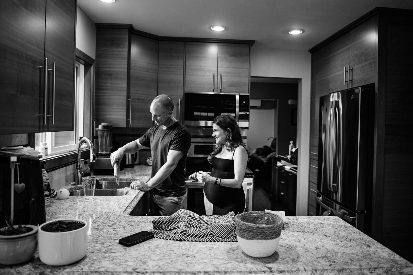 A pregnant mom-to-be makes dinner with her partner during a candid photojournalism unconventional maternity portrait session in Victoria BC