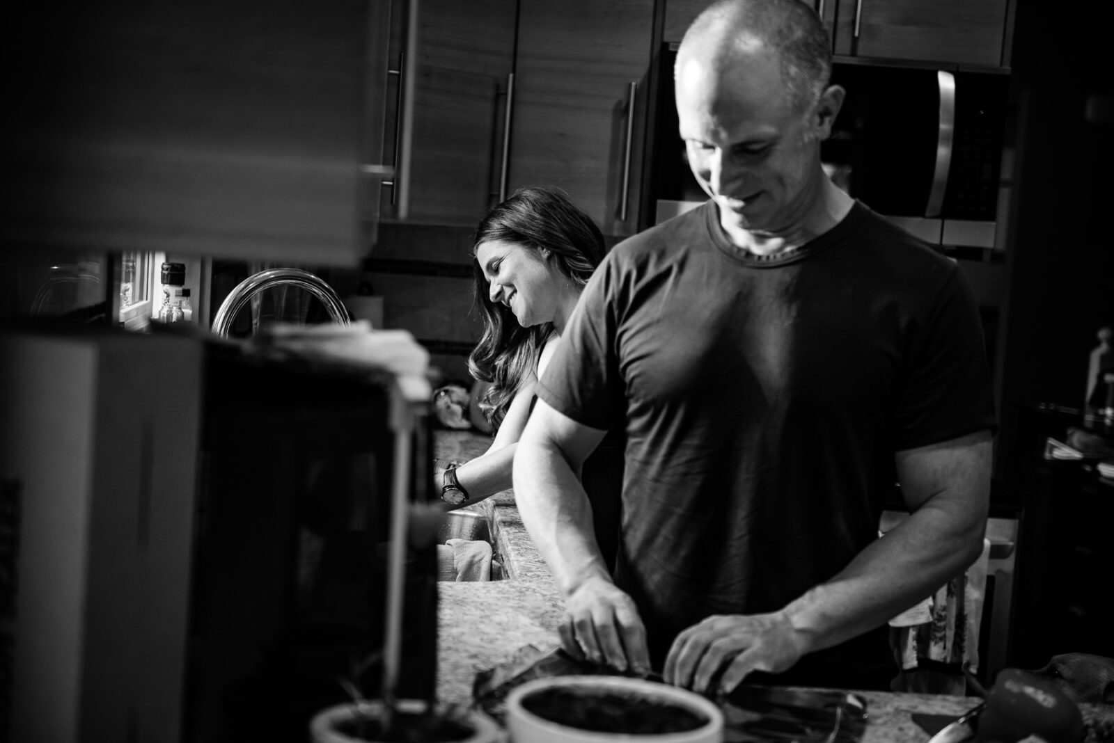 A couple laughs as they make dinner together during a documentary photo session in their home.