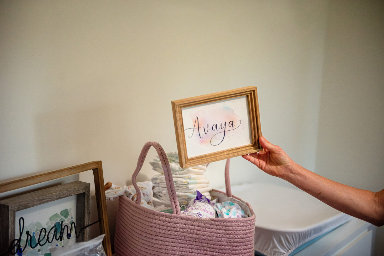A mom holds up a sign she will use to decorate her baby's nursery.