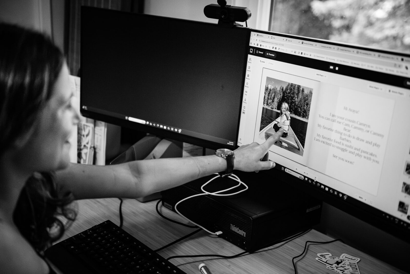 A couple looks at an album they are making on the computer.