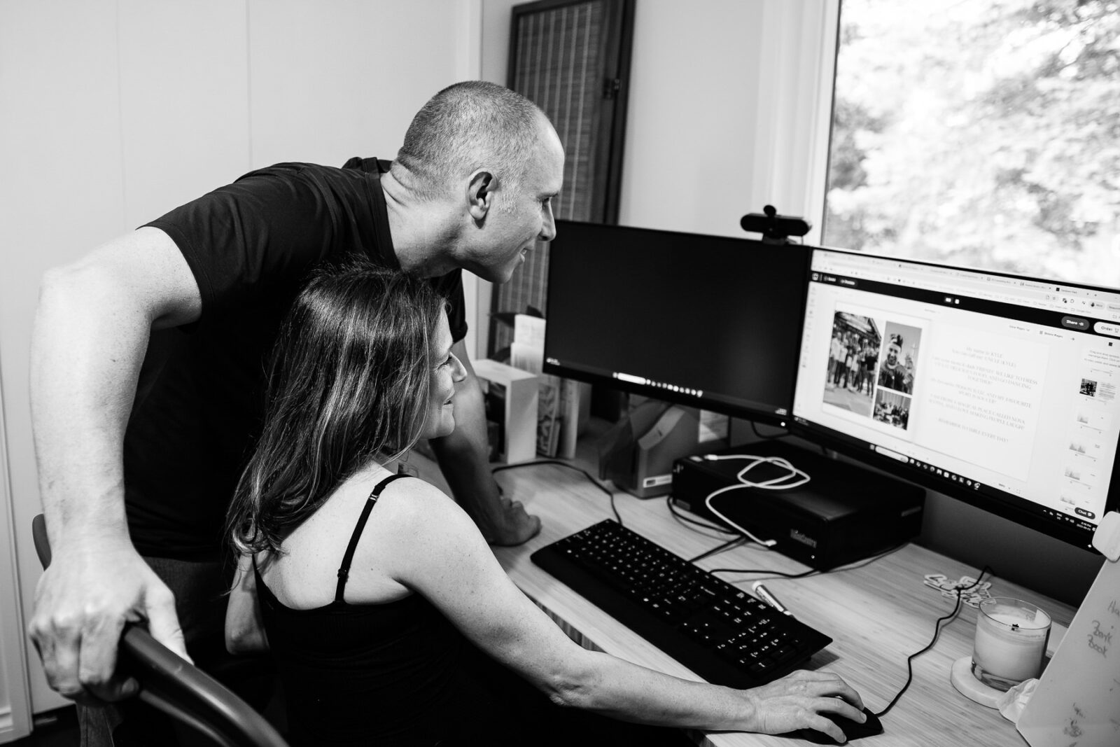 A couple looks at an album they are making on the computer.
