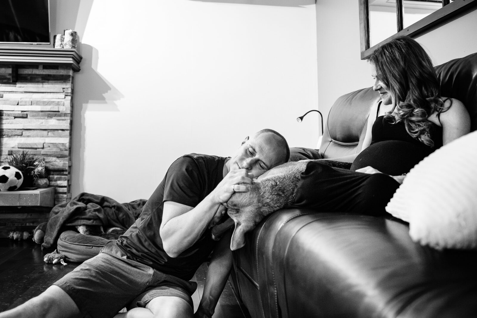 A couple snuggles in teh living room with their dog.