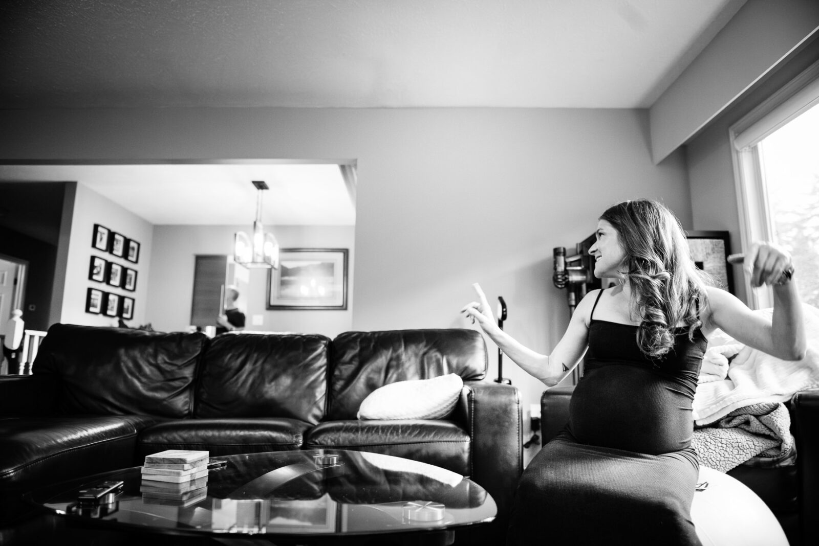 A pregnant woman during a maternity session bouncing on an exercise ball and laughing.