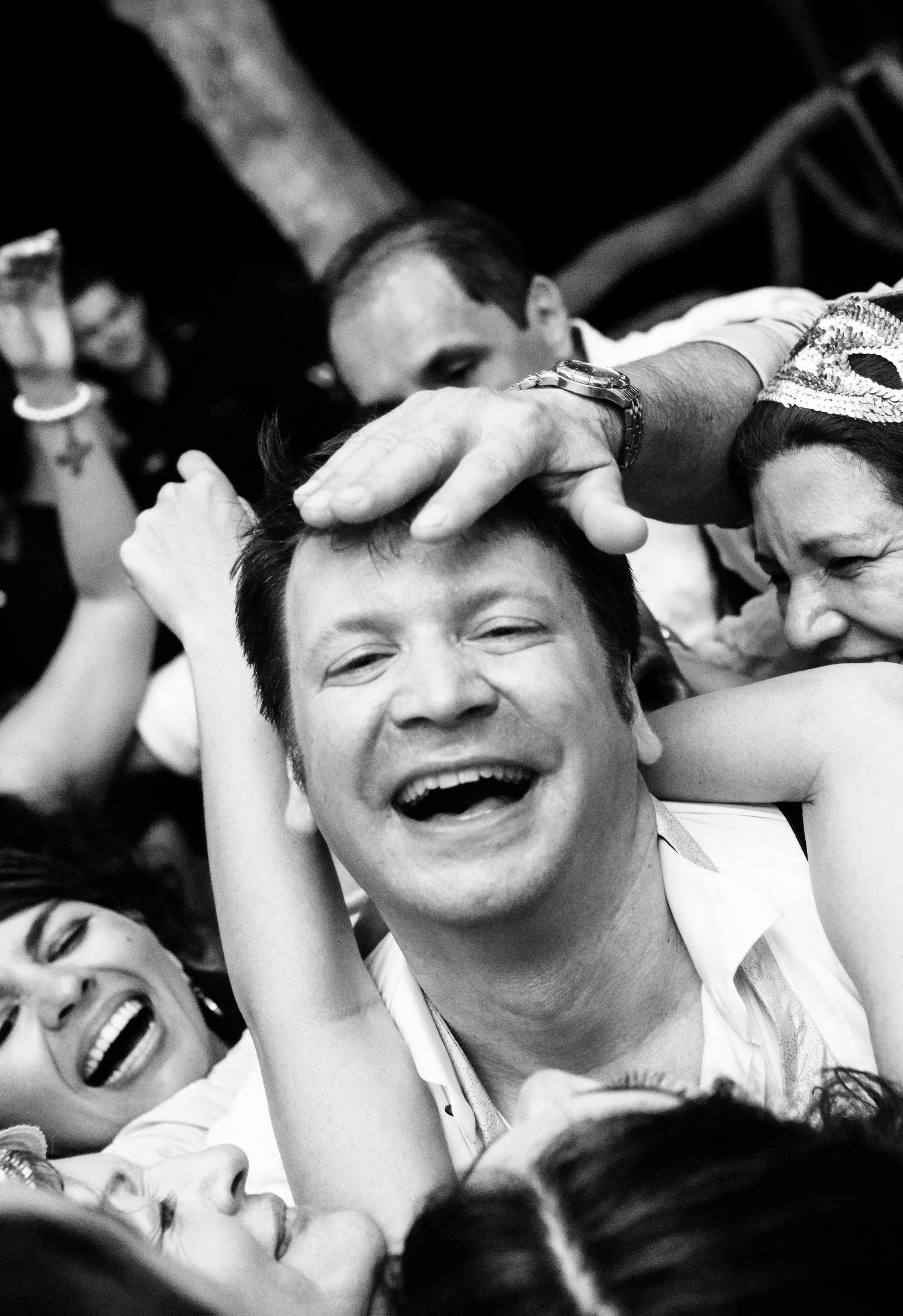 A groom is surrounded by people touching his head and hugging him while he is on the dance floor at his Victoria BC wedding reception.