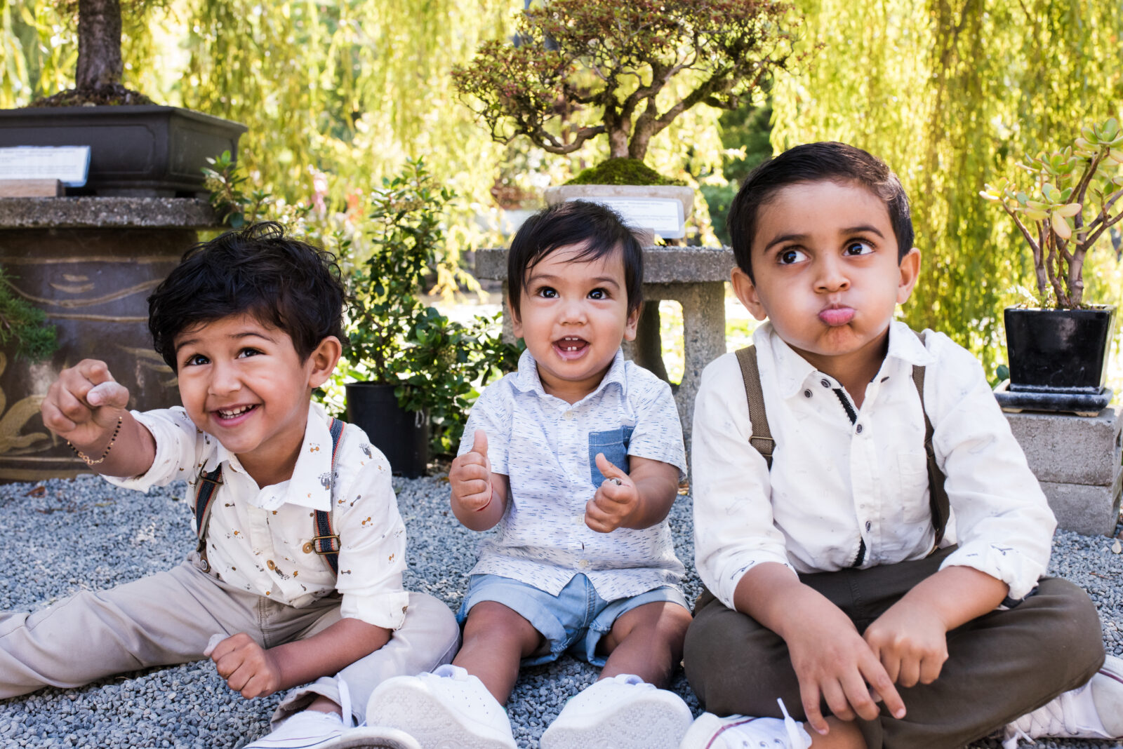 A cute family photo of toddler cousins all wearing suspenders and looking in different directions while at a one year old birthday party at Dr. Sun Yat-Sen Classical Chinese Garden in Vancouver BC