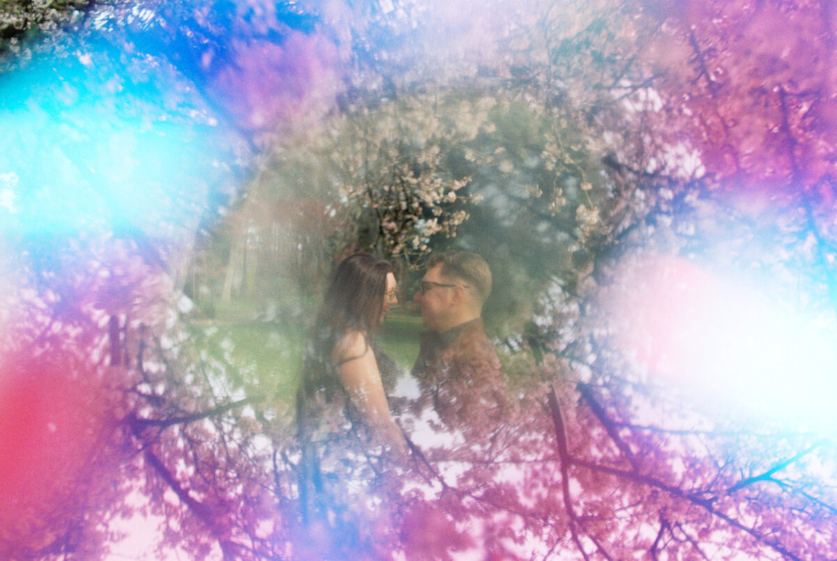 A creative reflection abstract engagement portrait of a couple surrounded by cherry blossoms and spring trees. 