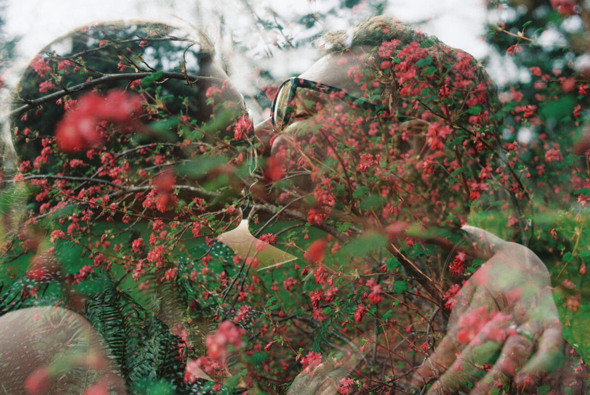 A double exposure film portrait of a couple kissing with spring flowers overlaid during their engagement portraits at Beacon Hill Park in Victoria BC