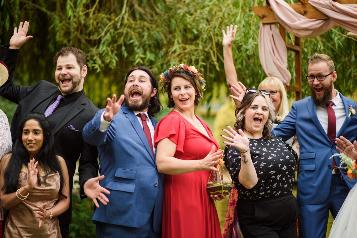 Happy fun wedding pary and family photo of everyone waving at the camera