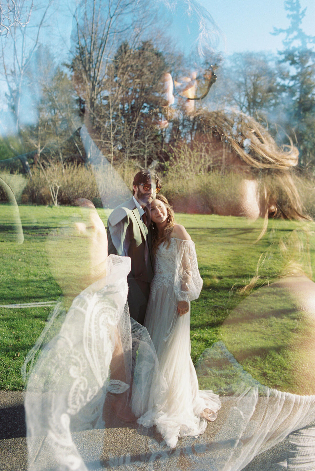 A creative wedding portrait photographed as a double exposure on film showing a closeup of the couple cuddling and a far-away shot of the couple standing in their boho wedding attire. This was shot as an editorial session at UVic in spring. 
