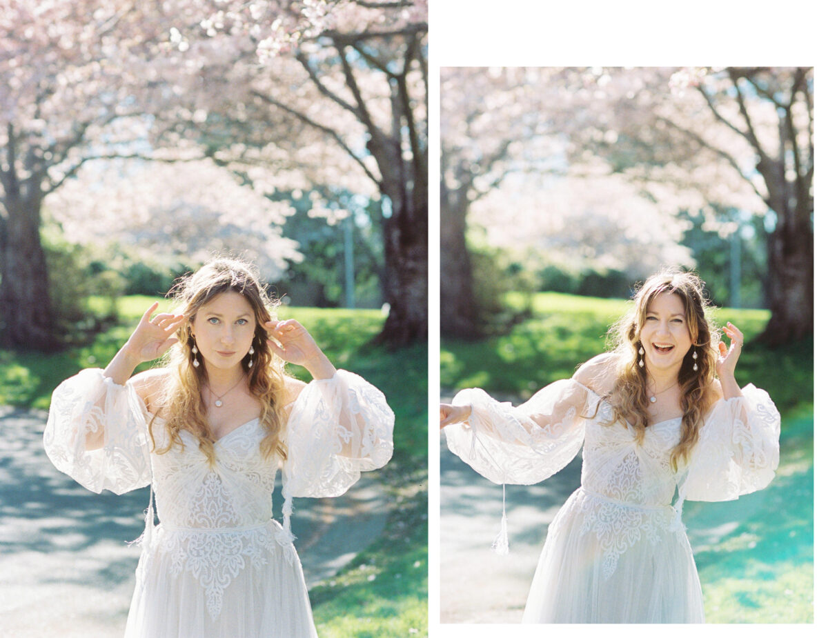 A bride plays for the camera during an editorial wedding photography session at Uvic. There are cherry blossoms in the background and the session was photographed on film. 