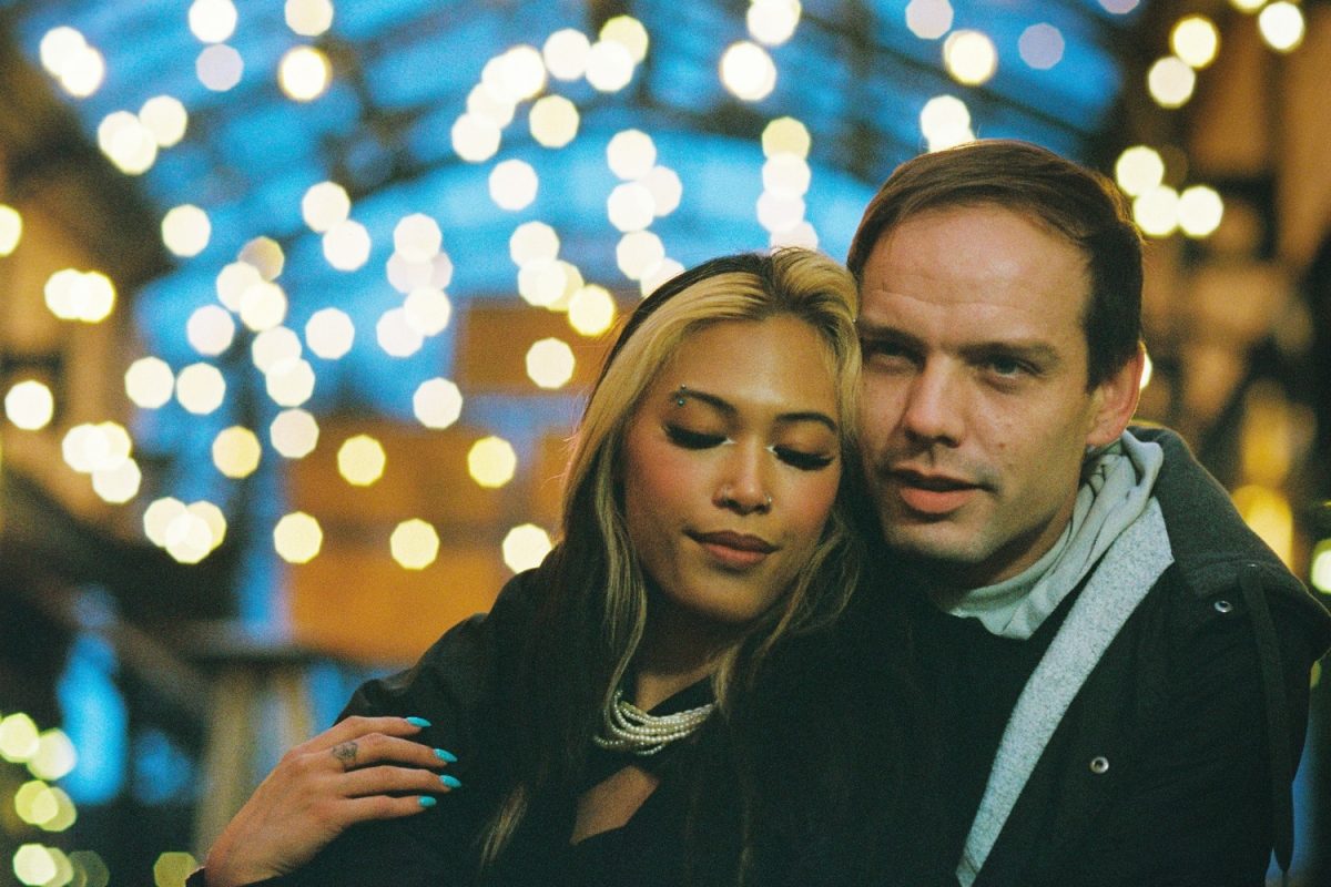 A couple surrounded by background bokeh lights at night are cuddling in an alley way in Victoria BC taken on Kodak Ultramax 35mm film.