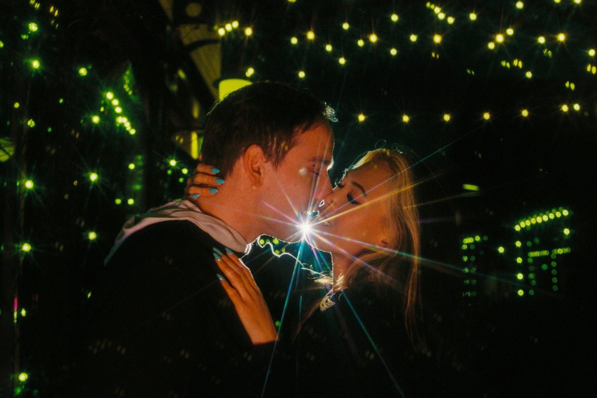 Off camera flash creating a star effect between a couple kissing surrounded by bokeh city lights in Victoria BC at night during a 10th anniversary photo session. The film used was Kodak Ektacolor Pro 800, which was formerly called Portra 800.