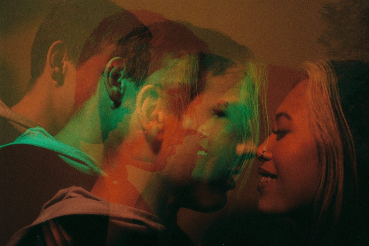 A double exposure of a couple snuggling lit by coloured video lights. This is a night anniversary session on Cinestill 800T film using a Pentax 645nii camera by a film photographer in Sidney BC