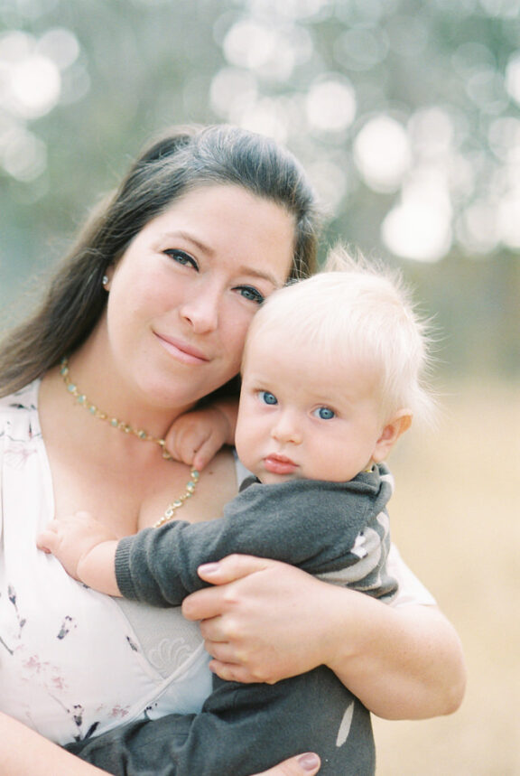 A mother holds her blue-eyed baby boy in Beacon Hill Park during a family portrait session taken with analog 35mm film. The film used for this photo was the pastel Fuji 400h.