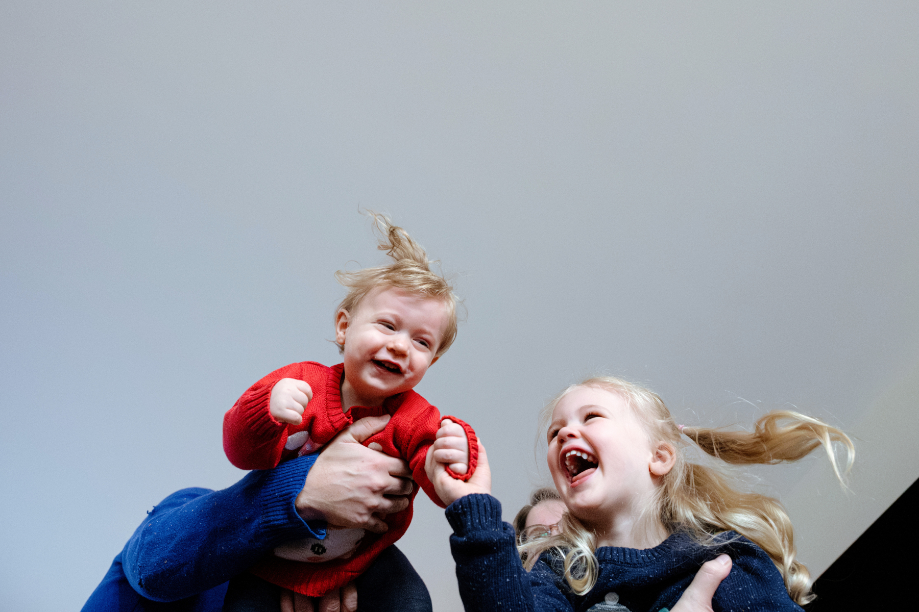 Kids are playing airplane while laughing in their home during a family mini session at Christmas in victoria BC