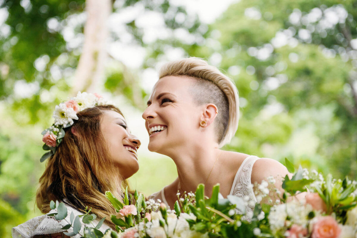 An LGBTQ couple has their first look and they are laughing during their Victoria BC wedding at Beacon Hill Park