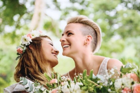 LGBTQ2S+ wedding photography in Victoria BC. Photo shows two women photographed in a candid way as they laugh together during their first look.