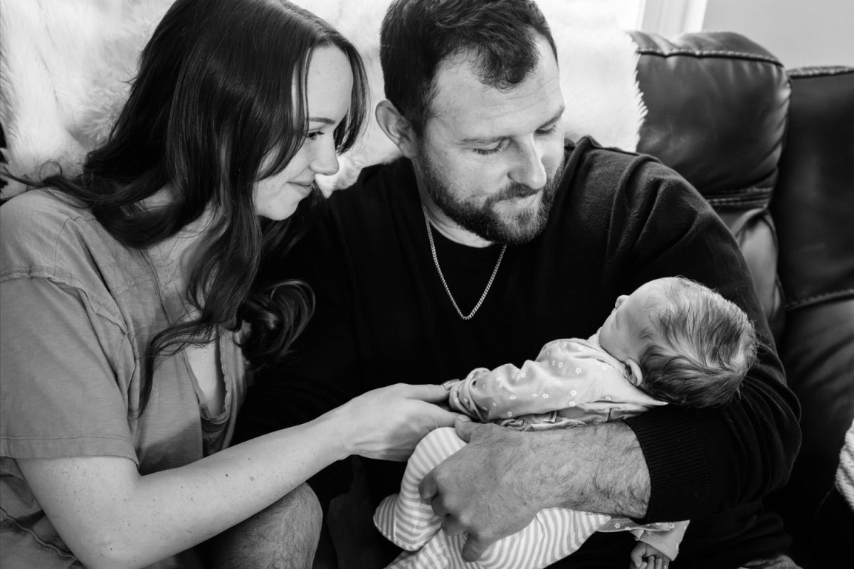 Newborn portrait of parents holding their baby daughter in their living room at home in Victoria BC