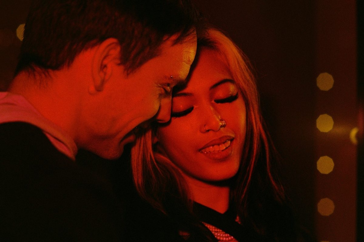 An anniversary photo shoot at night using Kodak Ultramax 400 35mm film scanned and developed by the Canadian Film Lab. A red light illuminates the couple as they cuddle.