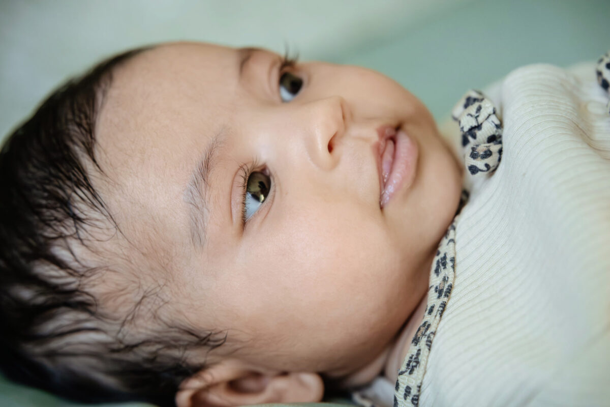 A cute baby with long eyelashes in Victoria BC taken during a candid baby portrait session at home.