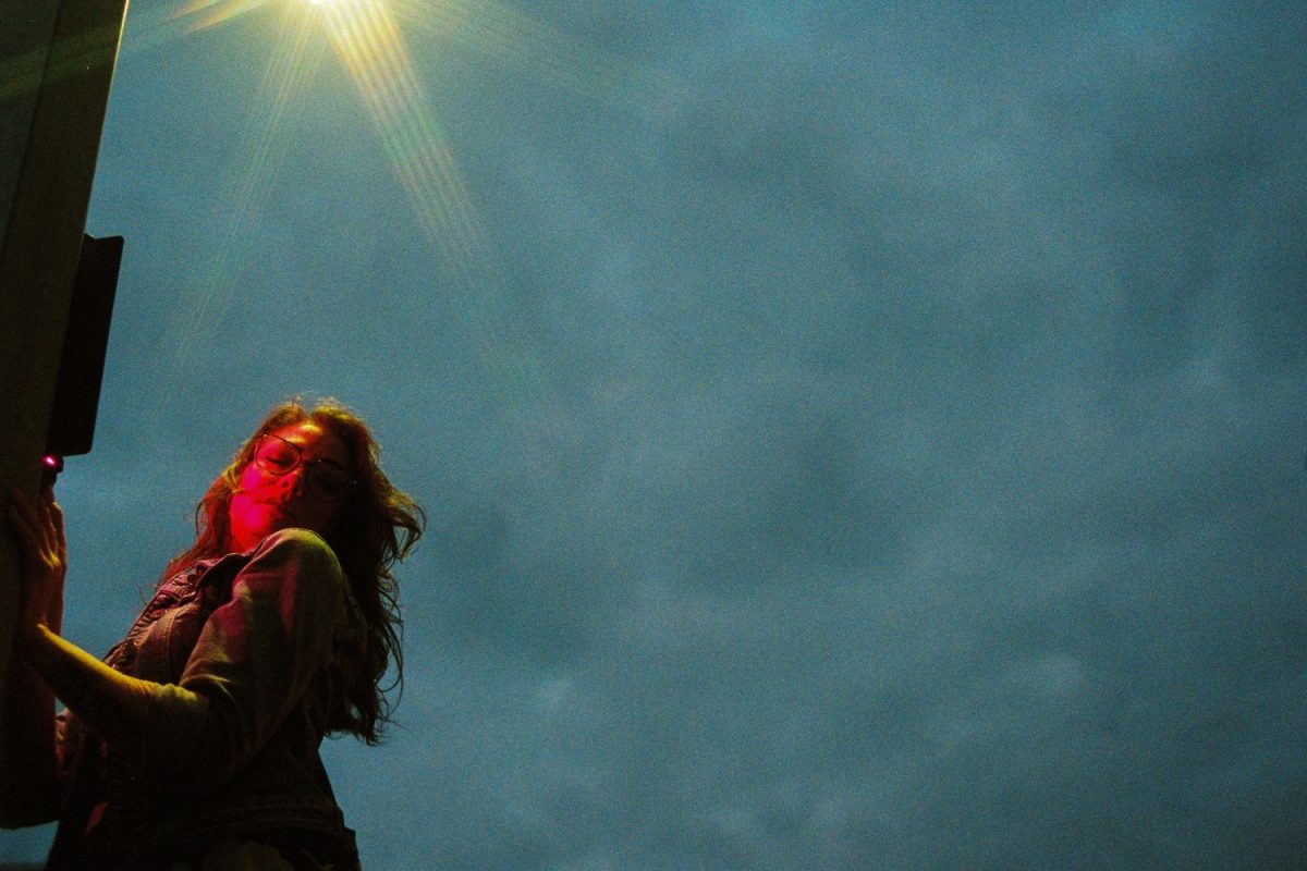 A woman poses next to a street light during blue hour in Victoria BC for her fashion cinematic portrait session. I illuminated Britt with a red video light on a tripod and I had an 8-point star filter on the lens to bring out the streaks from the street light. I find images like this need to be taken during blue hour before the sky gets too dark, otherwise it would be too much negative black space. Kodak Ektacolor Pro 800.