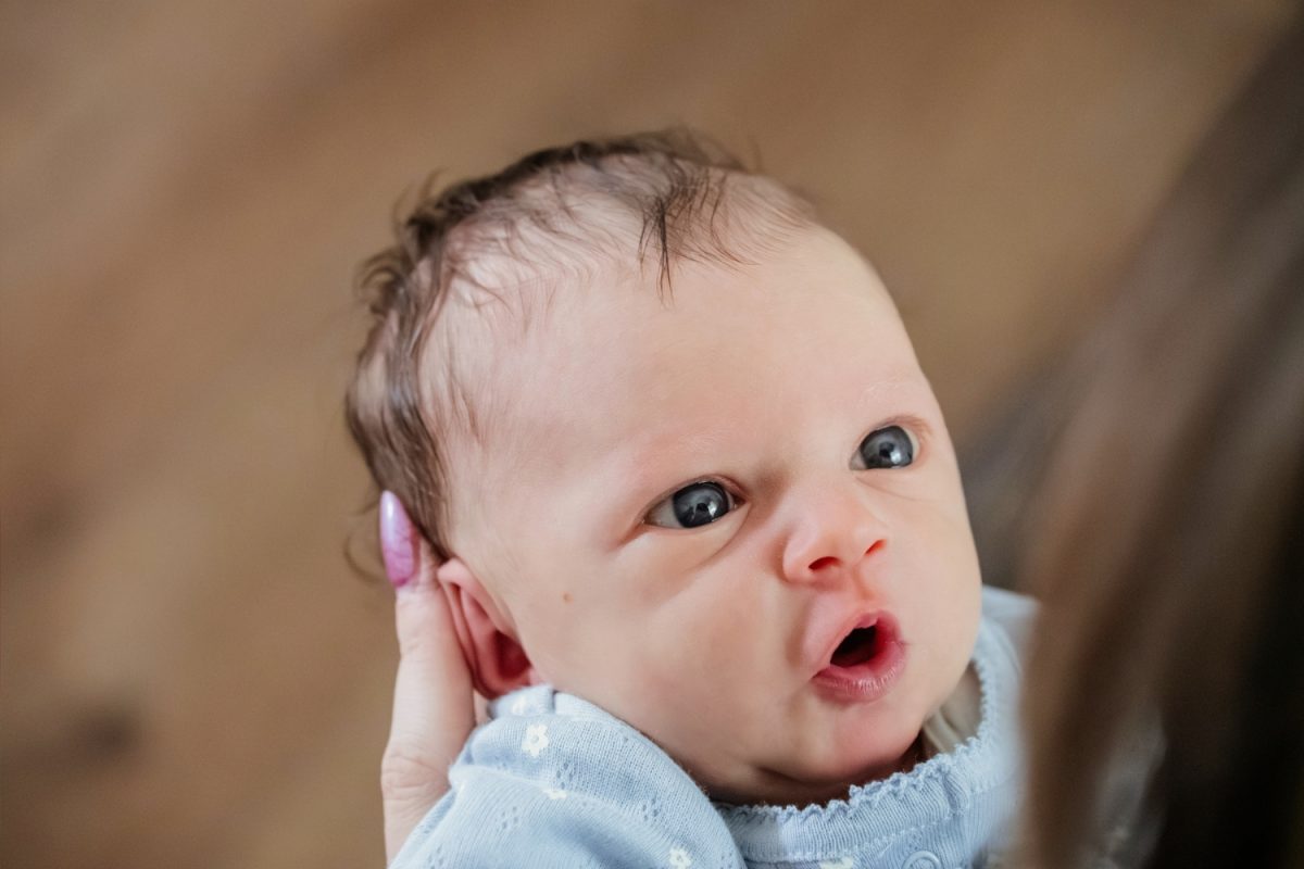 A newborn baby makes a cute funny face during a family portrait newborn session at their home in Colwood BC near Victoria